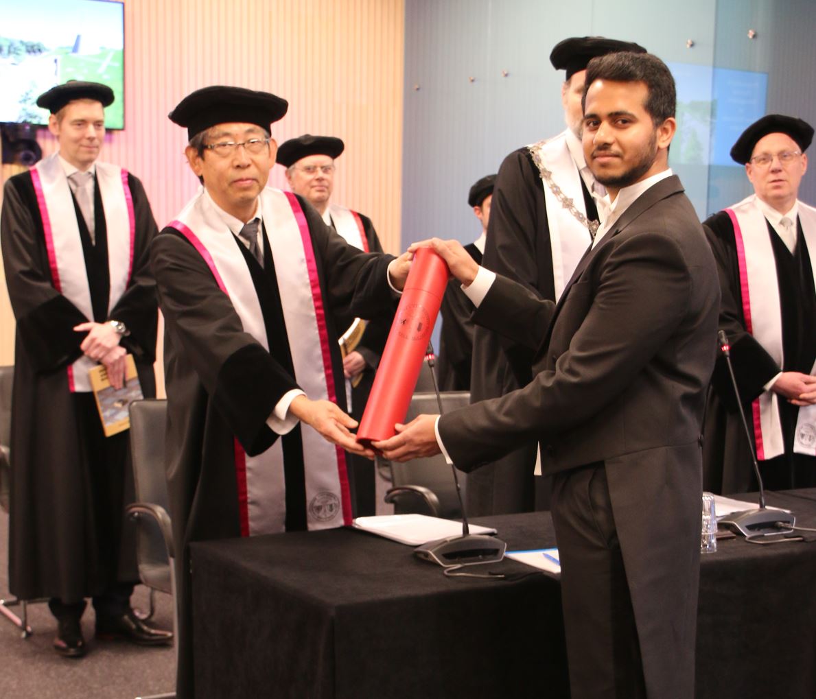 Young man receiving his university diploma from a professor